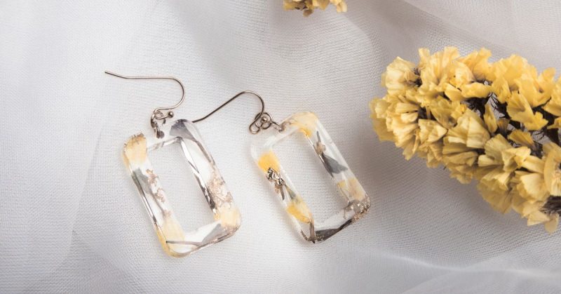 Clear resin earrings with yellow pressed flowers laid on soft white tulle