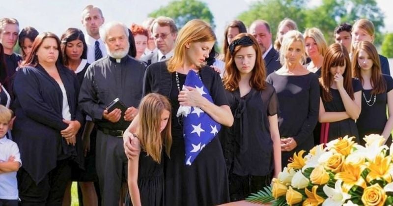 Family holding a folded American flag at a veteran's graveside service in Passaic, NJ